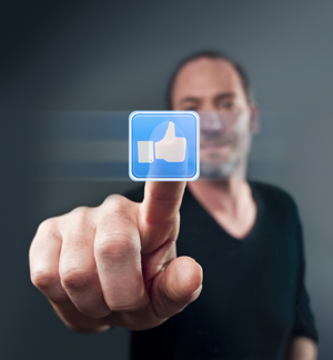 A picture of a man pressing the Facebook Like button.