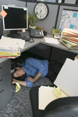 A picture of an employee taking a nap under his desk.