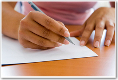 Person writing on a paper with a pen